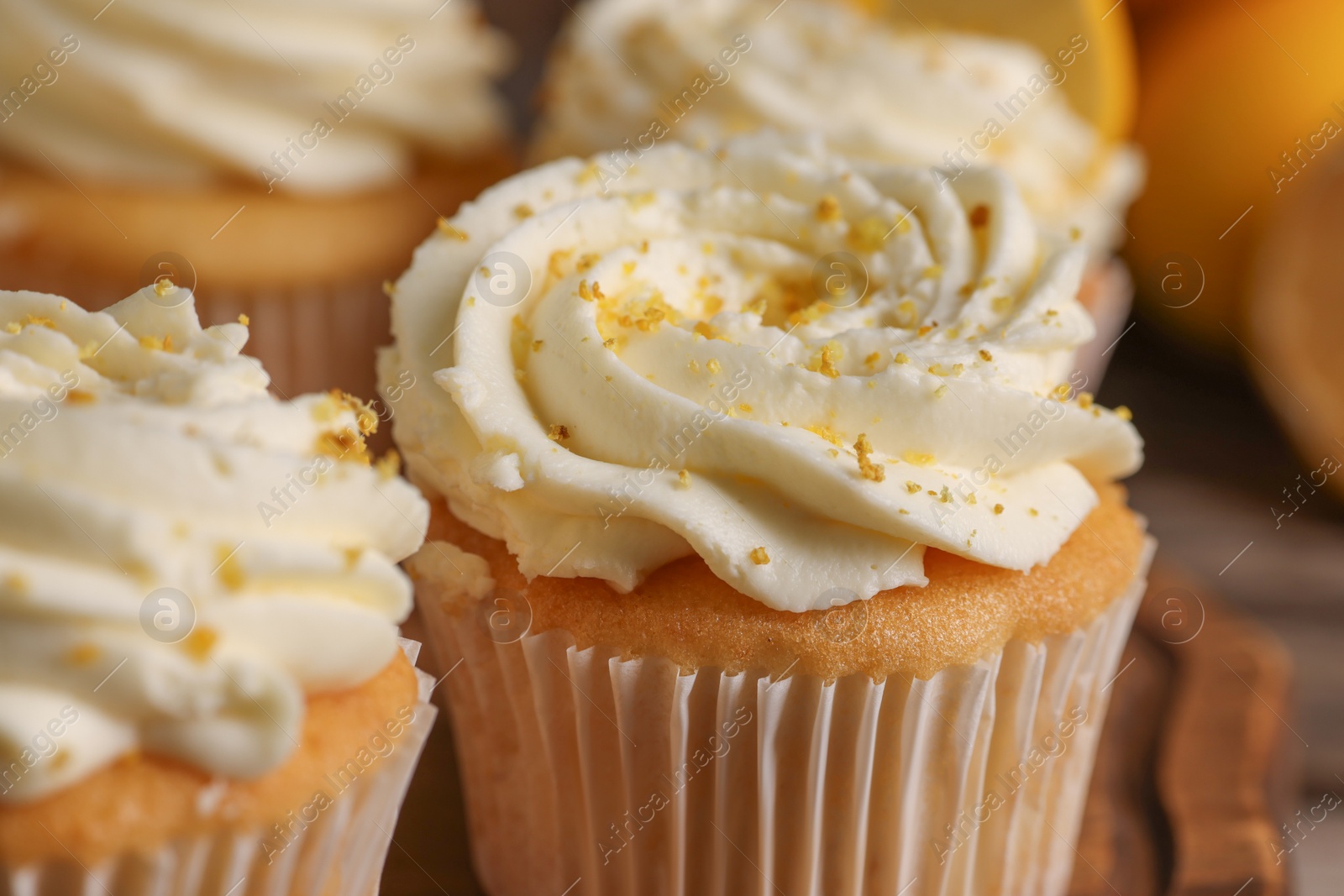 Photo of Delicious cupcakes with white cream and lemon zest, closeup