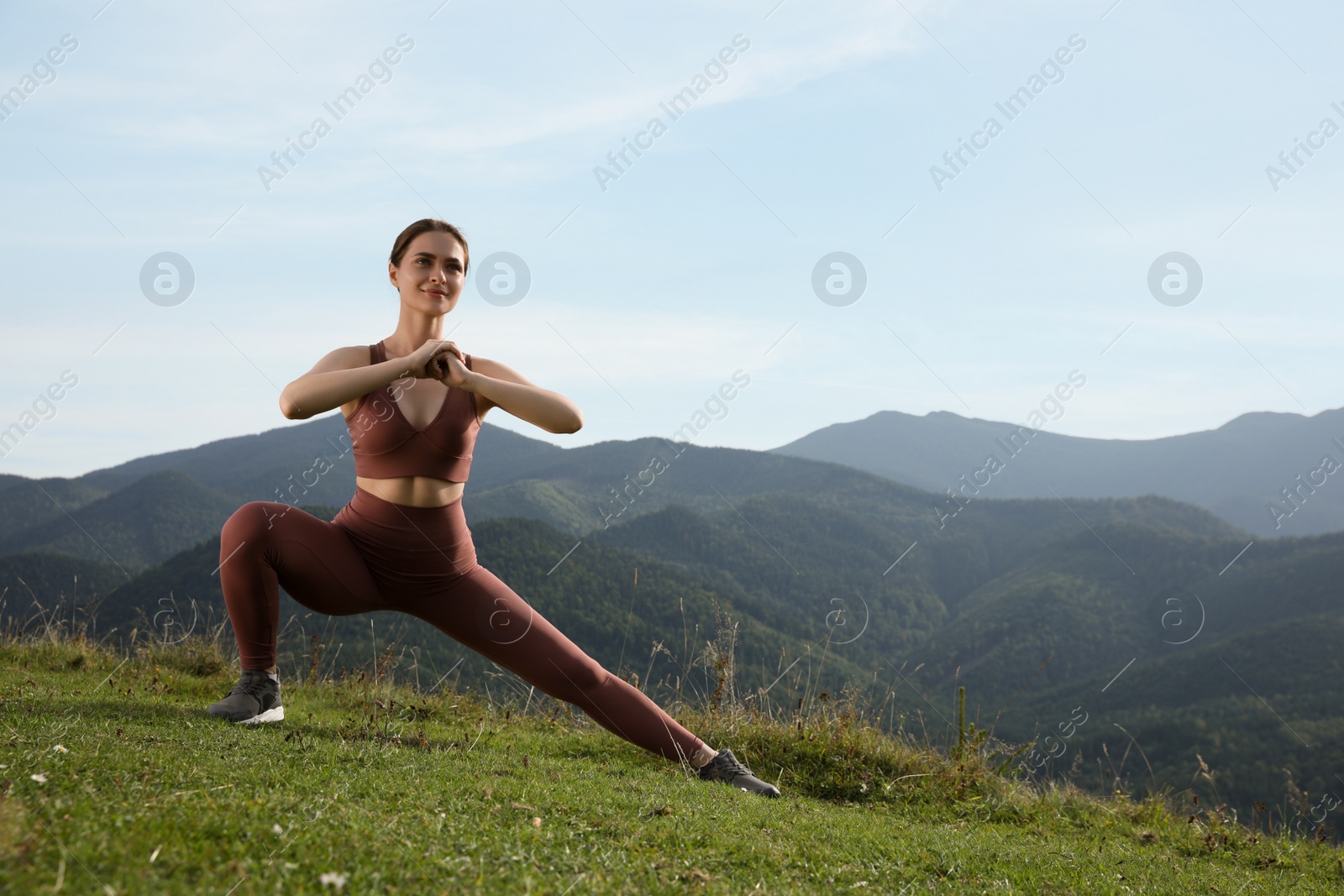 Photo of Young woman doing morning exercise in mountains, space for text