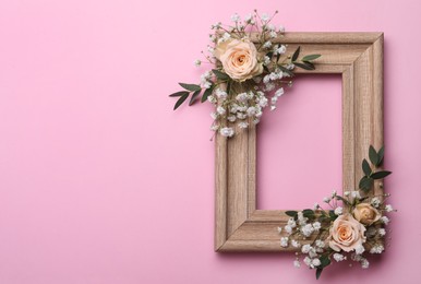 Photo of Wooden frame with gypsophila flowers, eucalyptus and roses on pink background. Space for text