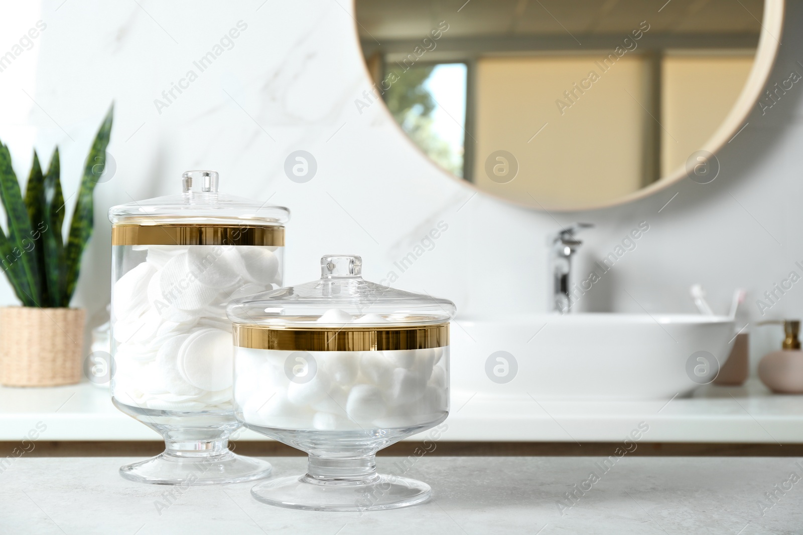 Photo of Cotton pads and balls on light grey table in bathroom