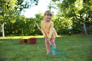 Cute little girl with rake in garden on spring day