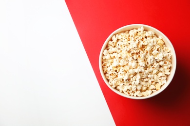 Photo of Tasty popcorn in paper cup and space for text on color background, top view. Cinema snack