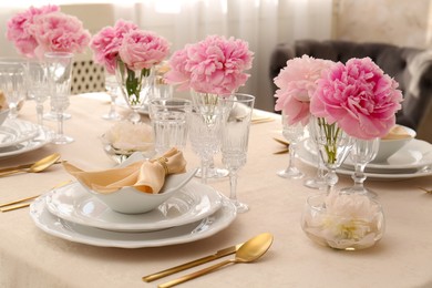 Stylish table setting with beautiful peonies and fabric napkins indoors