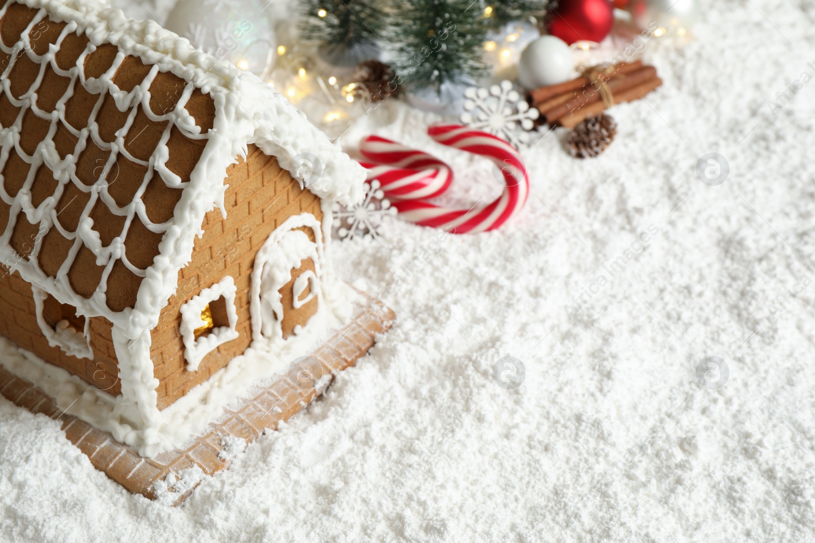 Photo of Beautiful gingerbread house decorated with icing on snow, space for text