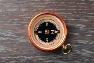 Photo of One compass on wooden table, top view