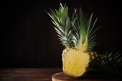 Photo of Whole and cut pineapples on wooden table. Space for text