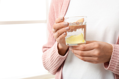 Photo of Woman with tasty lemon water near window, closeup