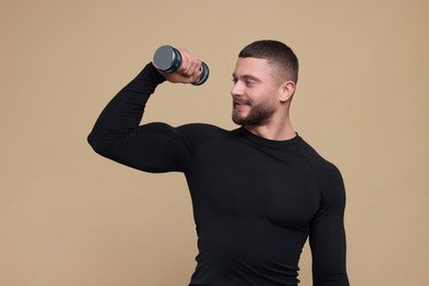 Handsome sportsman exercising with dumbbell on brown background