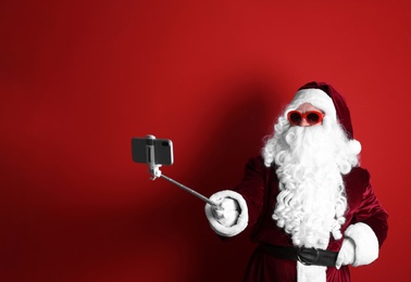 Photo of Authentic Santa Claus taking selfie on red background