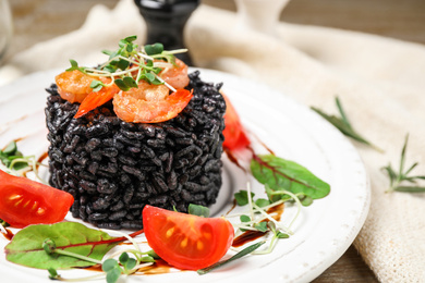 Delicious black risotto with seafood served on plate, closeup