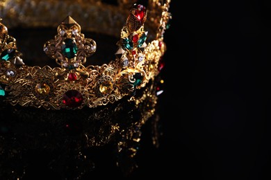 Photo of Beautiful golden crown with gems on dark mirror surface, closeup. Space for text