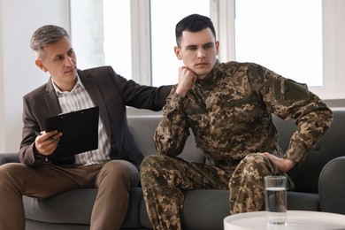 Photo of Professional psychotherapist working with military man in office