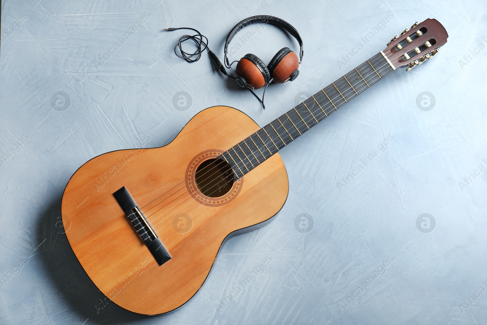 Photo of Beautiful classical guitar and headphones on color background, top view