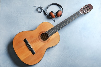 Photo of Beautiful classical guitar and headphones on color background, top view