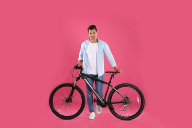 Photo of Handsome young man with modern bicycle on pink background