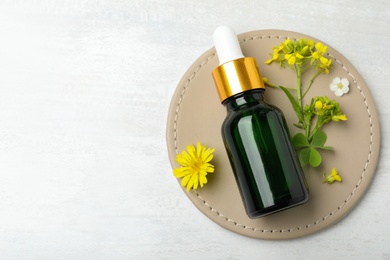 Photo of Bottle of essential oil with herbal ingredients on table, flat lay. Space for text