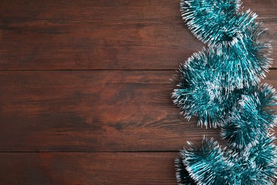 Photo of Light blue tinsel on wooden background, top view. Space for text