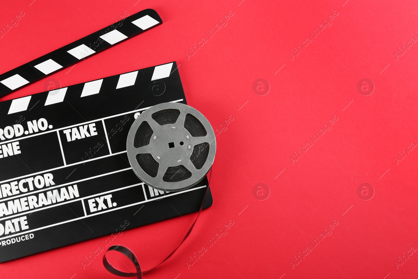 Photo of Movie clapper and reel on red background, top view. Space for text