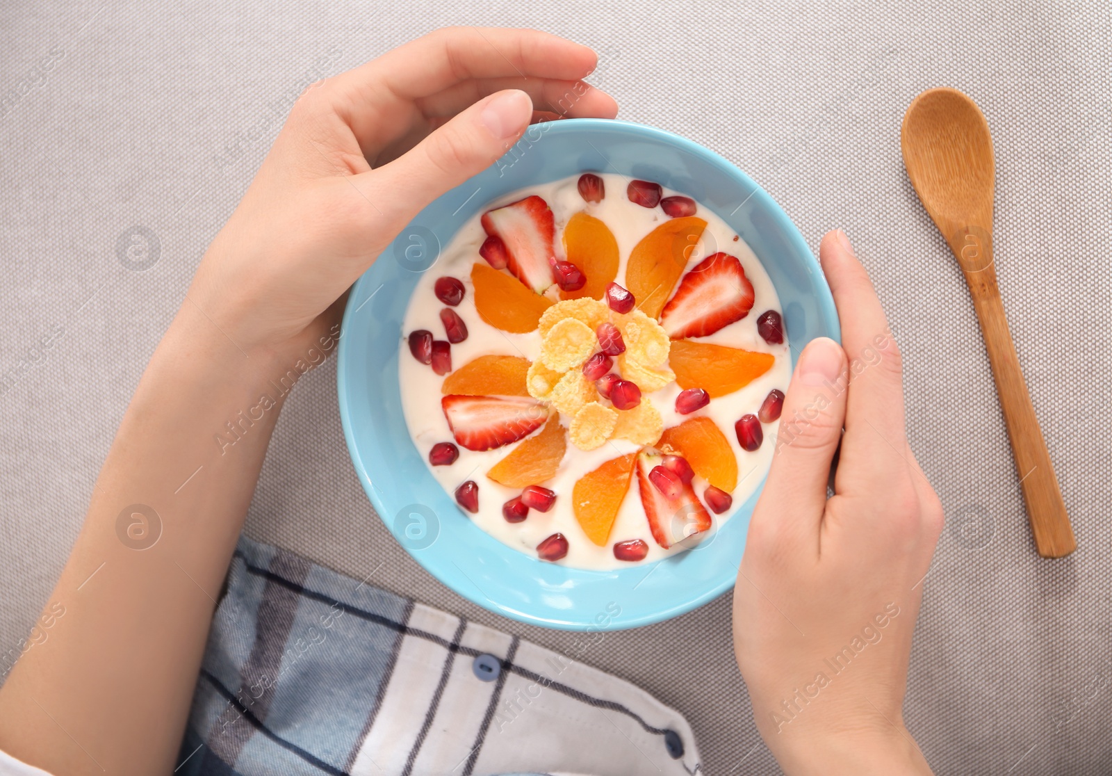 Photo of Young woman eating tasty yogurt with fruits, top view