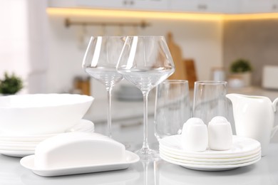 Photo of Set of clean dishware and glasses on table in kitchen