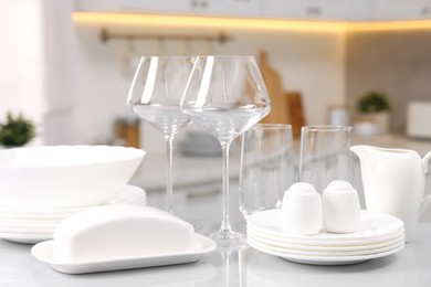 Set of clean dishware and glasses on table in kitchen