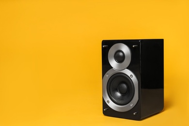 Photo of Modern powerful audio speaker on yellow background, space for text