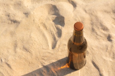 Photo of Bottle of beer on sandy beach, above view. Space for text