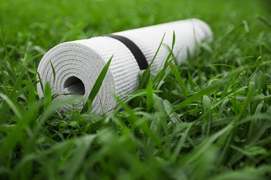 White karemat or fitness mat on green grass outdoors, closeup