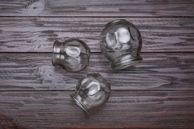 Photo of Glass cups on wooden table, flat lay. Cupping therapy