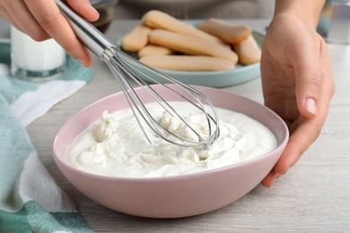 Photo of Woman making tiramisu cake at white wooden table, closeup