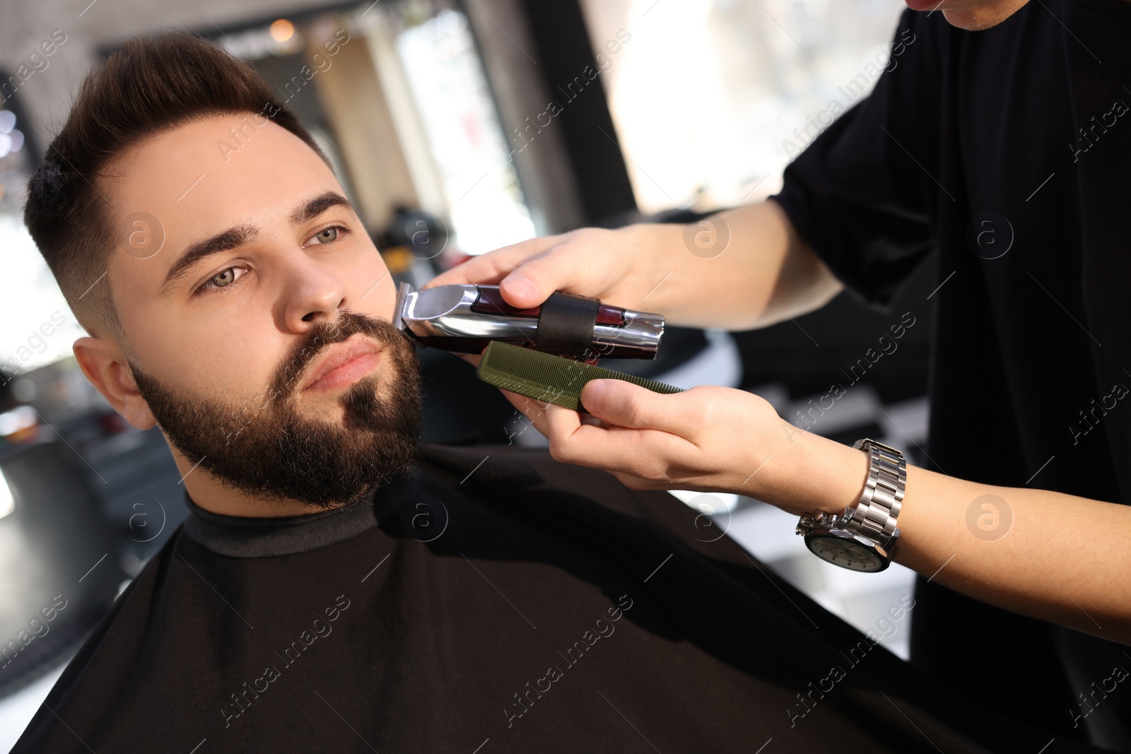 Photo of Professional hairdresser working with client in barbershop