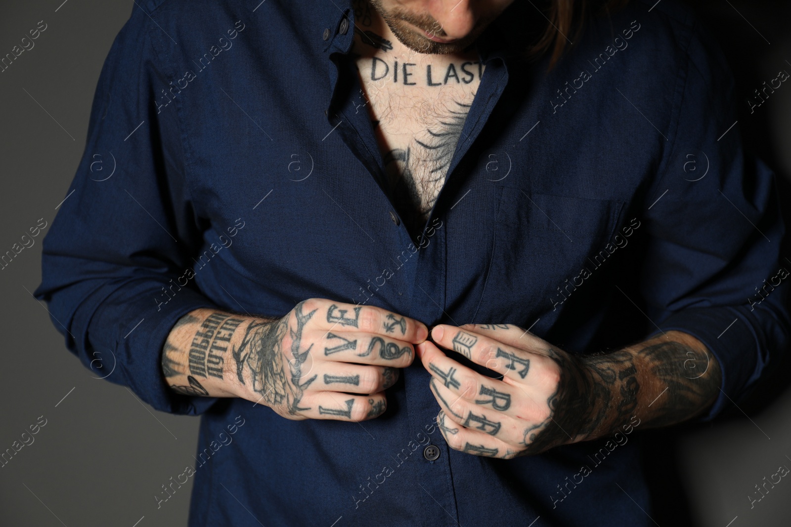 Photo of Young man with tattoos on body against black background, closeup