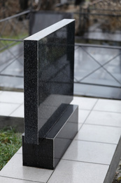 Photo of Black granite tombstone on cemetery. Funeral ceremony
