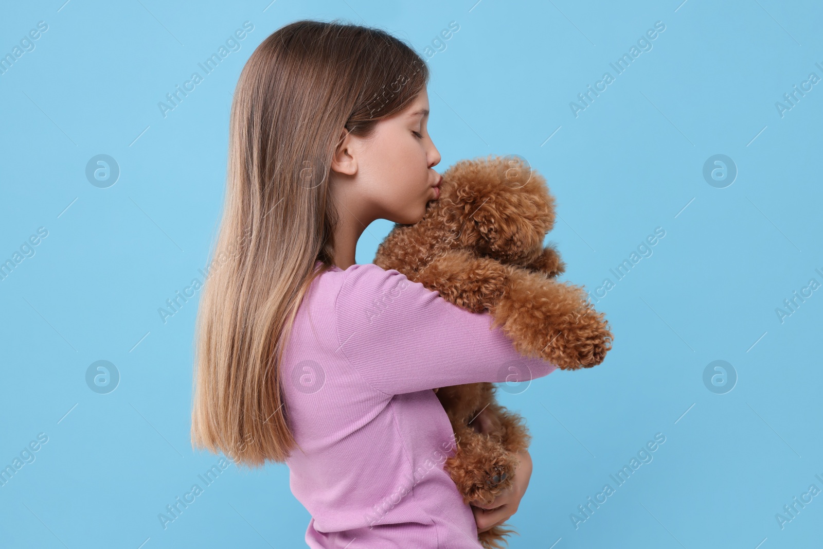 Photo of Little child with cute puppy on light blue background. Lovely pet