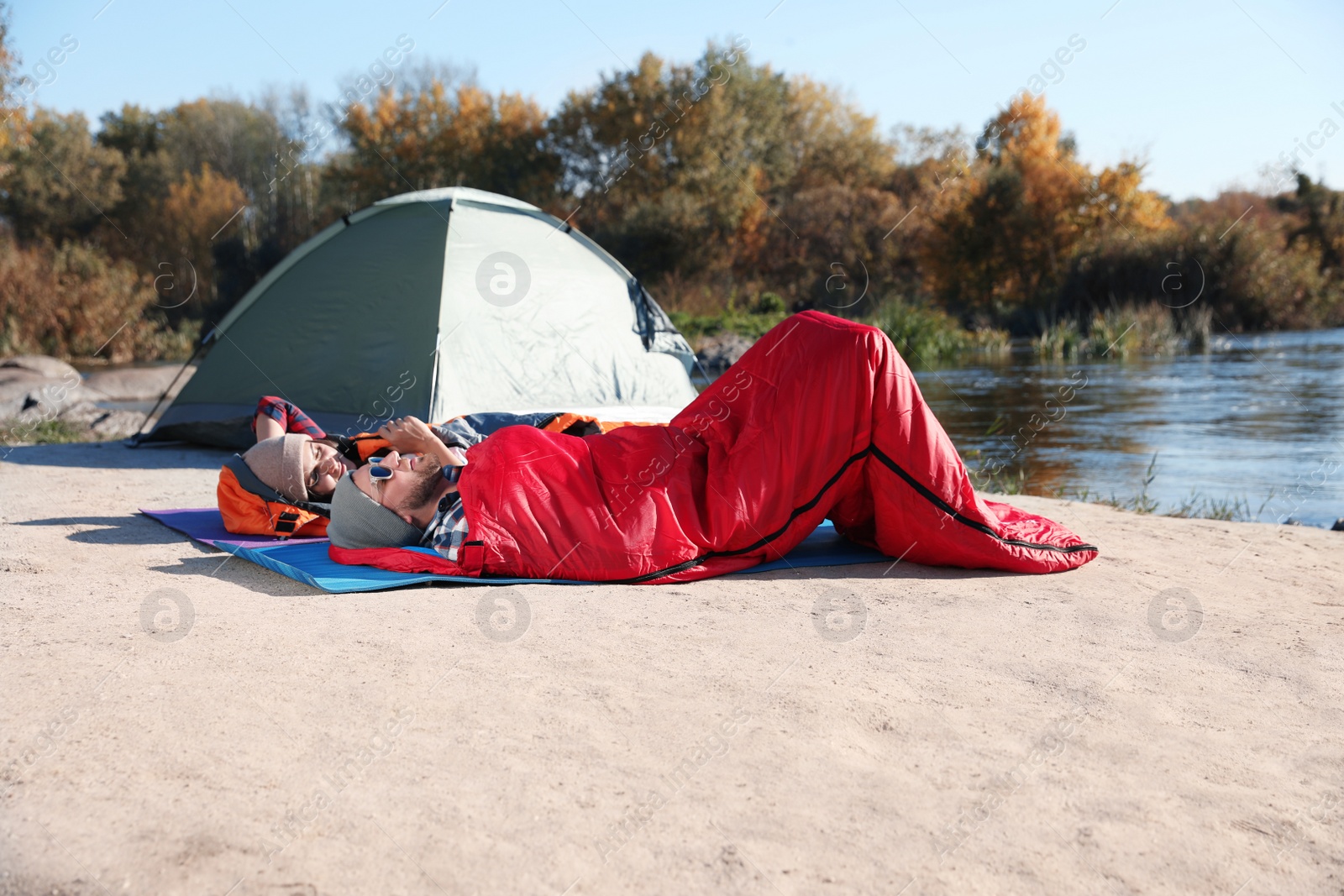 Photo of Campers lying in sleeping bags on wild beach