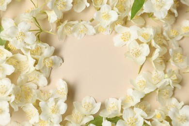 Photo of Frame of aromatic jasmine flowers on beige background, flat lay. Space for text