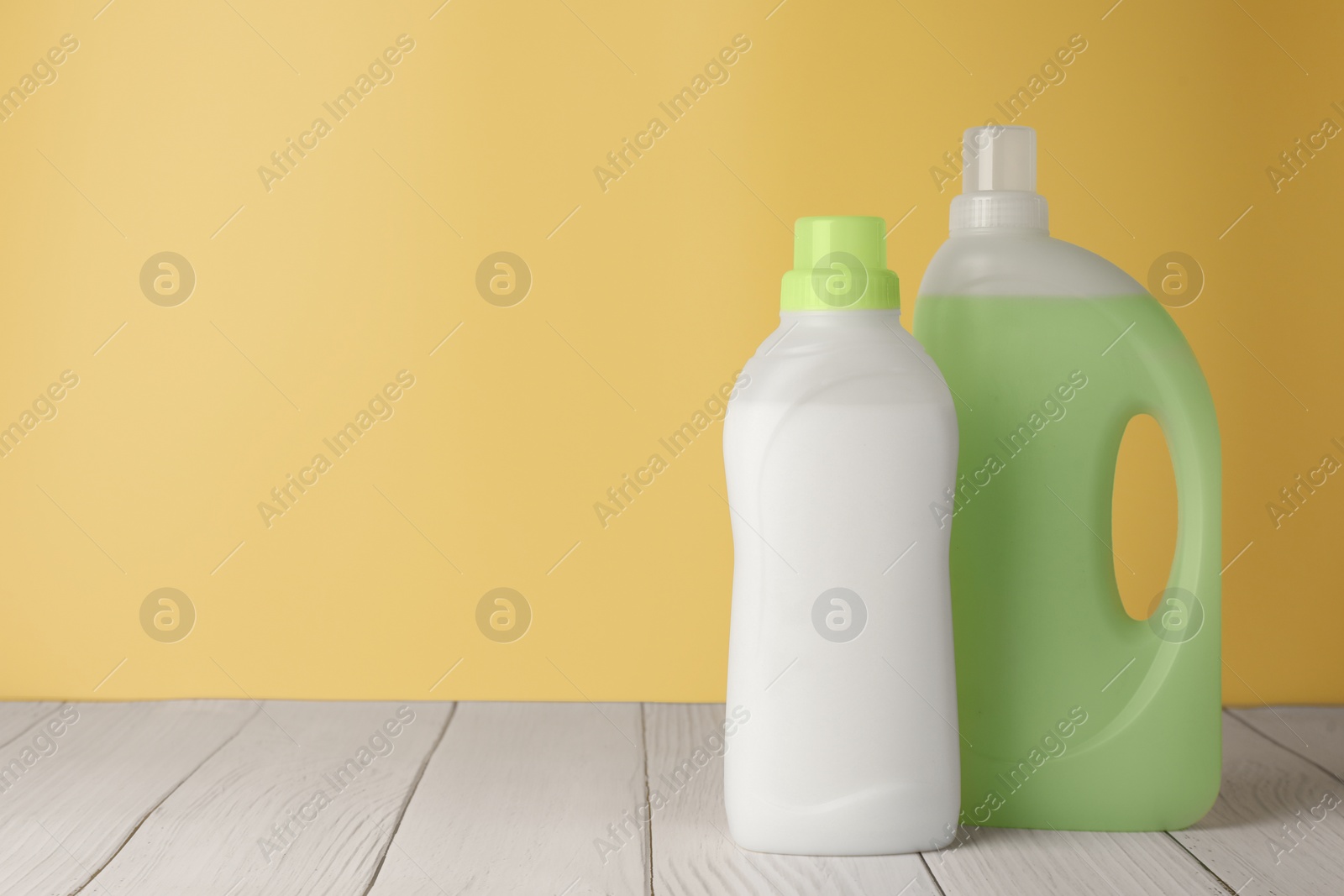 Photo of Bottles of fabric softener on white wooden table, space for text