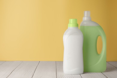 Photo of Bottles of fabric softener on white wooden table, space for text