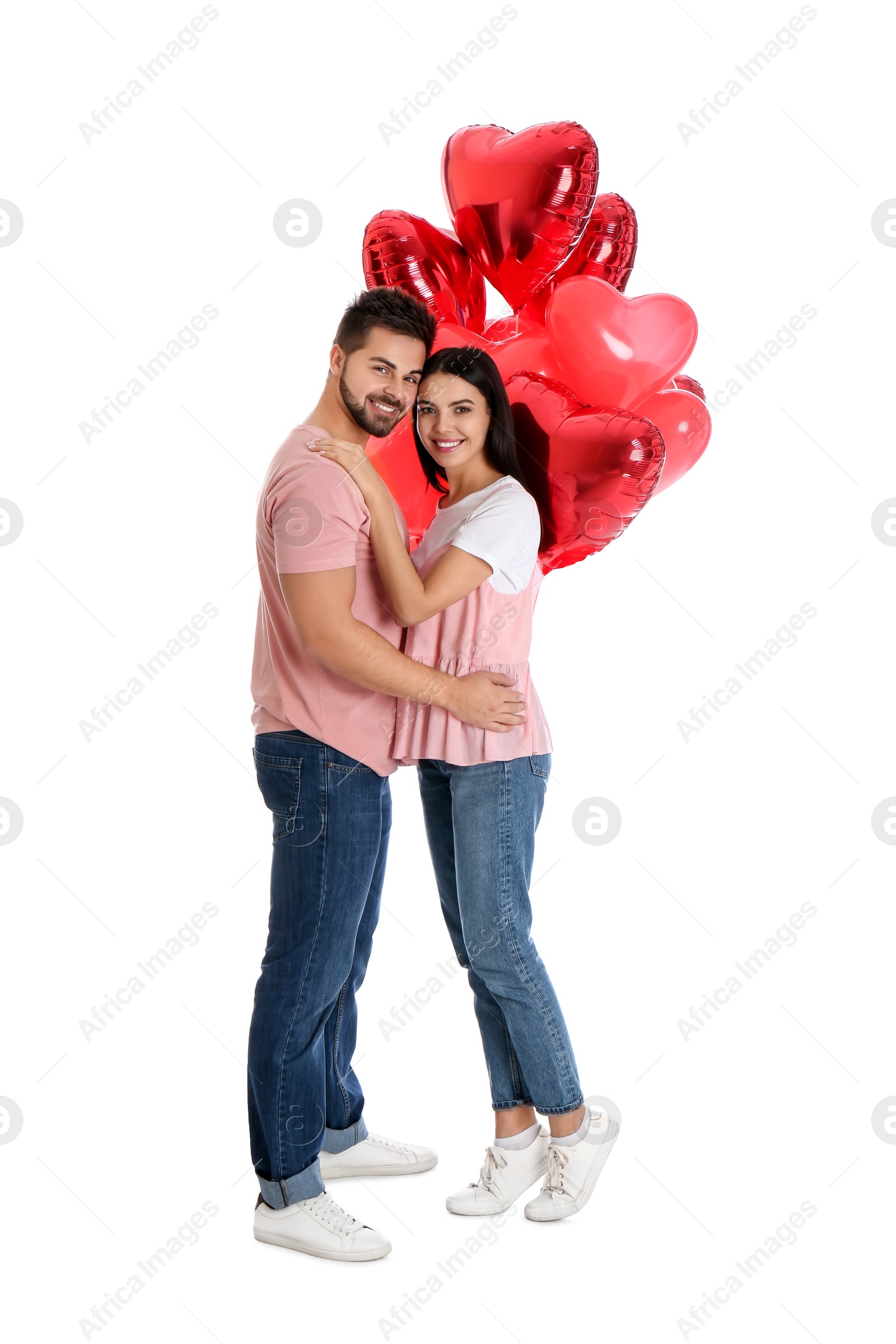 Photo of Happy young couple with heart shaped balloons isolated on white. Valentine's day celebration