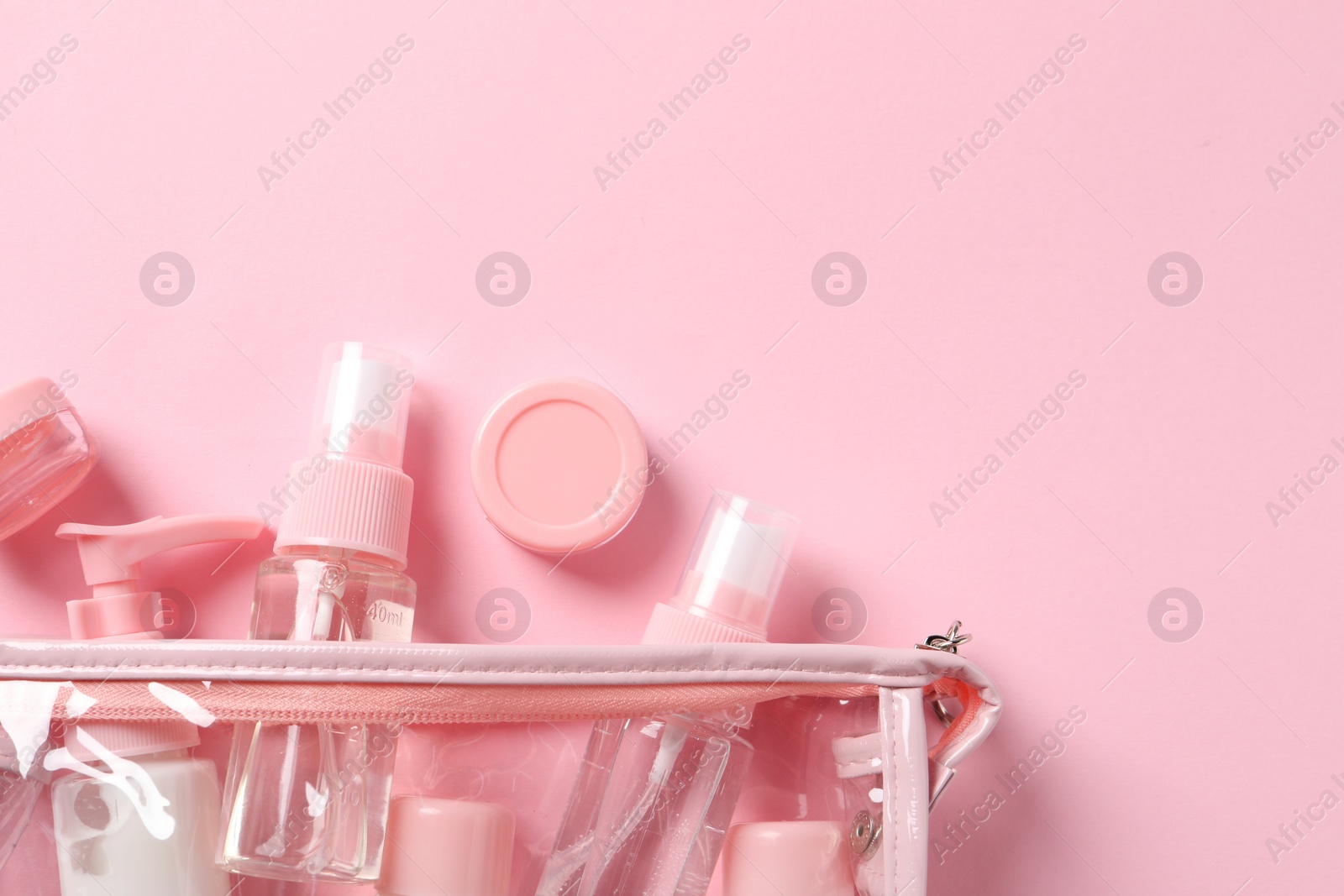 Photo of Plastic bag with cosmetic travel kit on pink background, flat lay. Space for text