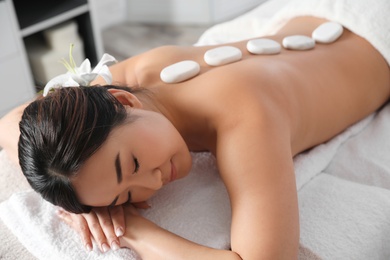 Photo of Beautiful Asian woman getting hot stone massage in spa salon