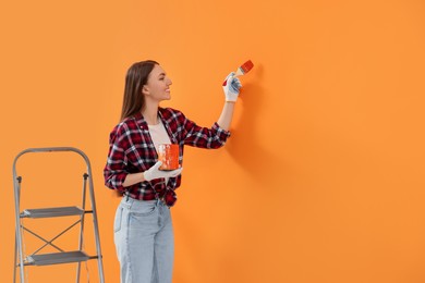 Designer painting orange wall with brush, space for text