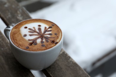 Cup of aromatic coffee on wooden bench outdoors in winter, closeup. Space for text