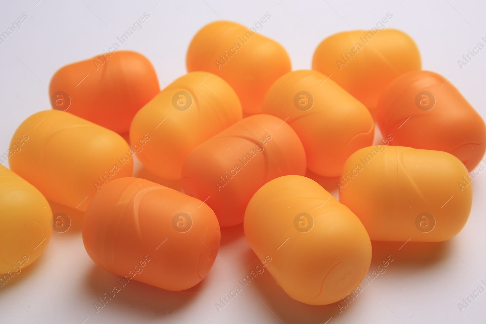 Photo of Sveti Vlas, Bulgaria - June 30, 2023: Orange plastic capsules from Kinder Surprise Eggs on white background, closeup