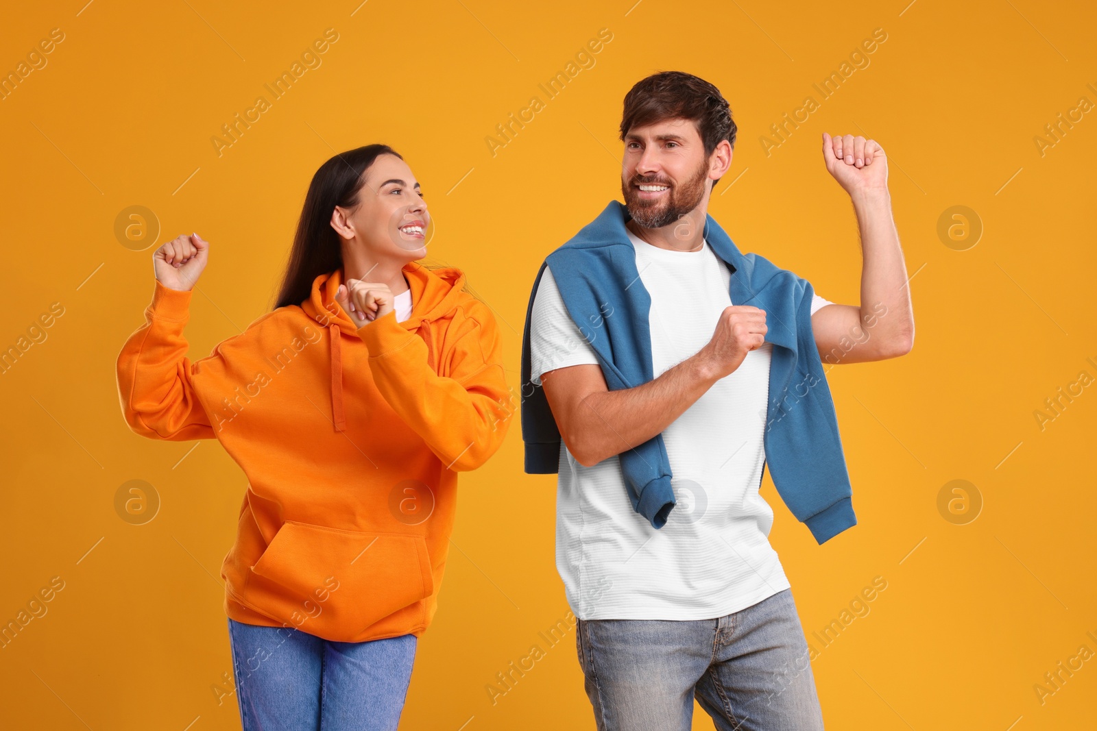 Photo of Happy couple dancing together on orange background