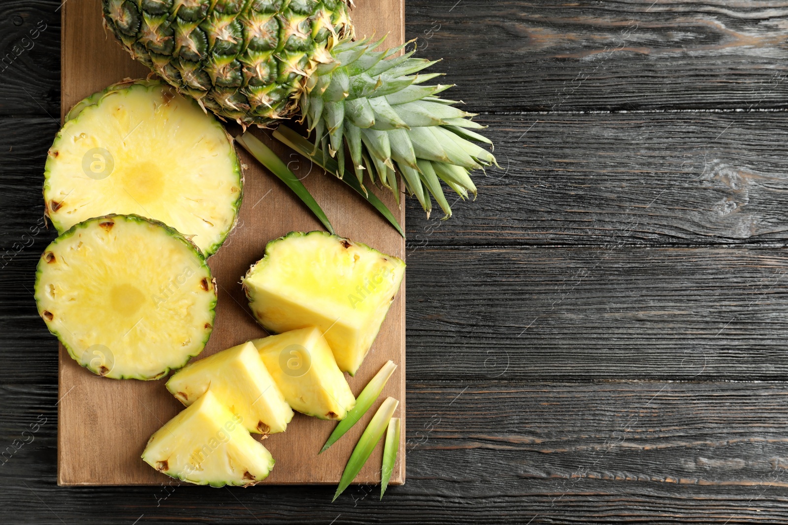 Photo of Wooden board with fresh sliced pineapple on table, top view