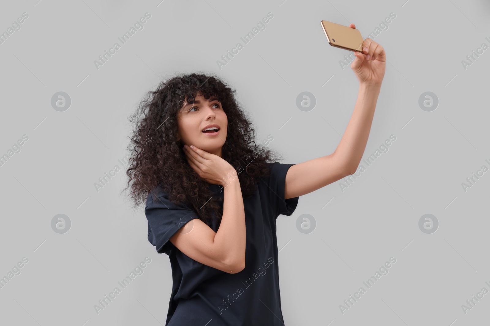 Photo of Beautiful young woman taking selfie on light grey background