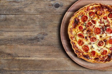 Delicious homemade quiche with prosciutto and tomatoes on wooden table, top view. Space for text