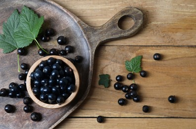 Ripe blackcurrants and leaves on wooden table, flat lay