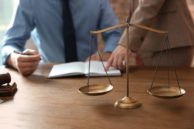 Photo of Notaries working at table in office, focus on scales of justice. Law concept